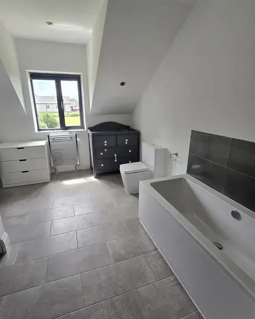 Bathroom with a panelled bath, storage unit and large-format grey floor tiles