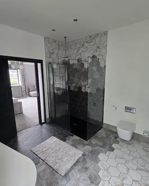 Walk-in shower finished in hexagon marble-effect tiling with a black frame