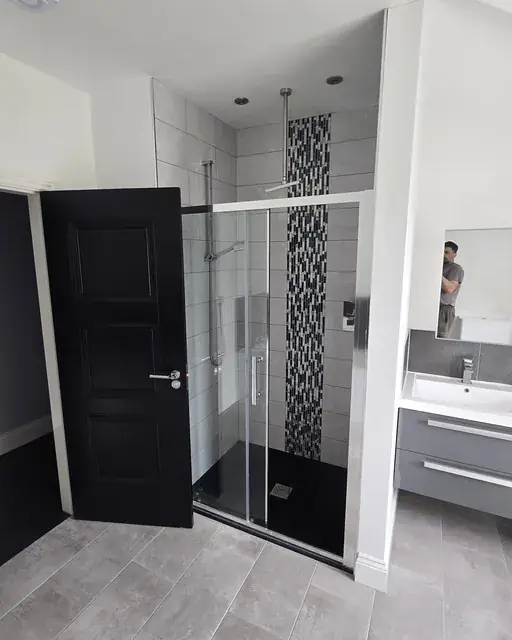 Family bathroom with sliding shower enclosure, tiled walls and a vanity unit