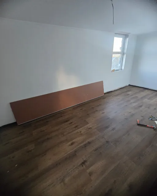 Bedroom with dark oak-effect flooring laid wall to wall