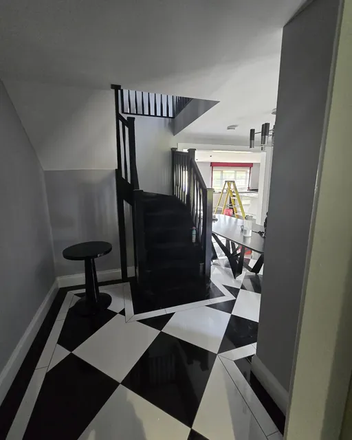 Hallway with black and white chequerboard floor tiles and a black staircase
