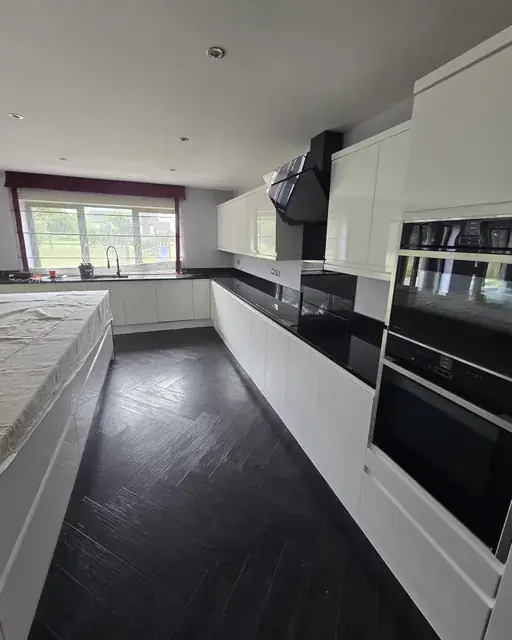 Fitted kitchen with dark herringbone flooring and integrated appliances